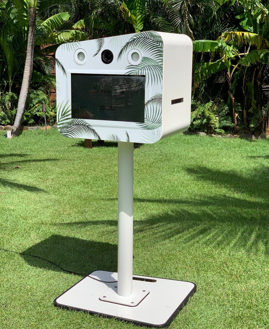 White photo booth with palm-leaf design set up in a tropical garden